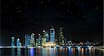 Beautiful cityscape of Singapore CBD on a clear night with stars and reflection off water.
