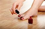 Woman applying red nail polish isolated on herself