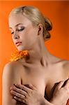 attractive and sensual young girl with an orange rose on her nacked shoulder looking down