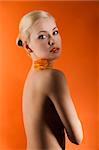 attractive and sensual young girl with an orange rose on her nacked shoulder looking in camera with stunning eyes