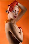 young and sensual nude woman with red gloves and a orange rose on her shoulder looking down