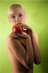 fashion and glamour shot of a nude young woman with apple on green background