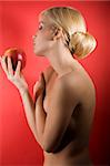 fashion shot of a glamour sensual girl looking a red apple against colored background