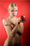 fashion shot of a glamour sensual girl keeping a red apple on red background