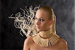 blond young amazon looking in african style with necklace on dark background