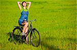 Happy young woman with a vintage bicycle on a green meadow