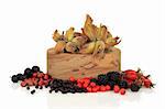 Wild food of autumn of rose hip, elderberry, hawthorn, blackberry, rowan and sloe berry, with  hazelnuts in an olive wood bowl, isolated over white background.