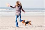 Girl playing with her beagle puppy  on beach