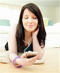 Dreamy woman listening music lying on the floor at home