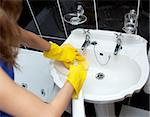 Woman cleaning a bathroom's sink with a sponge and detergent spray