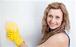 Smiling woman cleaning a bathroom with a sponge