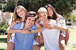 group of happy young men's piggybacking thier girlfriends in the park