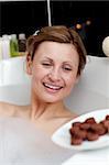 Happy woman eating chocolate while having a bath in a spa center