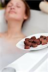 Attractive woman eating chocolate while having a bath in a spa center