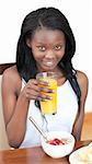 Smiling Afro-American drinking an orange juice in the living-room