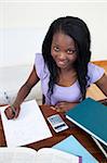 Smiling Afro-American teen girl doing her homework at home