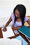 Concentrated Afro-American teen girl doing her homework at home
