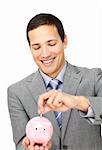 Attractive businessman saving money in a piggy-bank against a white background