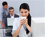 Assertive Businesswoman drinking a coffee at her desk in the office