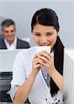 Smiling confident Businesswoman drinking a coffee at her desk in the office