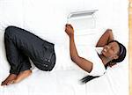 Smiling teen girl using a laptop lying on her bed at home