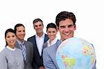 Assertive businessman holding a globe in front of his team against a white background