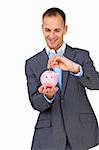 Charismatic businessman saving money in a piggybank against a white background