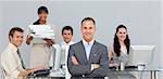 Self-assured manager with folded arms with his team in the background