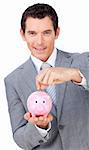 Confident businessman saving money in a piggybank against a white background