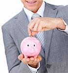 Close-up of a businessman saving money in a piggybank against a white background