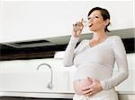 portrait of italian 6 months pregnant woman drinking water in kitchen. Horizontal shape, copy space