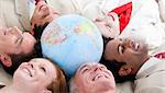 Multi-ethnic business people lying on the floor around a terrestrial globe