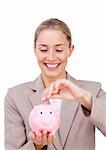 Charming businesswoman saving money in a piggybank isolated on a white background