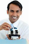 Smiling businessman consulting a business card holder in the office