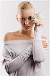 beauty portrait of young cute blond girl with white top and some flowers near face