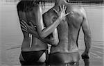Man and woman are embracing standing in water / black and white photo