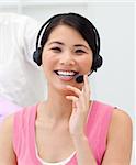 Positive Asian businesswoman talking on headset in the office