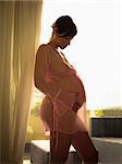 italian pregnant woman touching stomach and leaning on window. Vertical shape, copy space