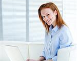 Smiling business woman working on a laptop computer in the office