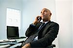 African American businessman holding cellphone to ear looking bored.