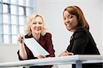 Businesswomen sitting at office desk going over paperwork.