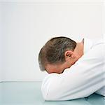 Caucasian middle aged businessman with head down on desk.