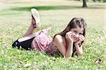 happy cute girl  laying on a grass field and looking stright ,outdoor