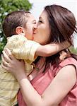 Children kissing his mom in the park, outdoor