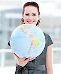 Assertive businesswoman holding a terrestrial globe in the office