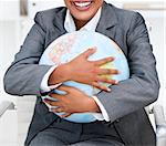 Close-up of a smiling businesswoman holding a terrestrial globe in the office