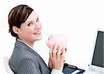 Cheerful businesswoman holding a piggy-bank in the office
