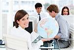 Confident businesswoman holding a globe in the office