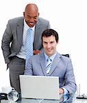 Ethnic manager assisting his colleague at a computer against a white background