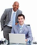 Smiling manager assisting his colleague at a computer against a white background